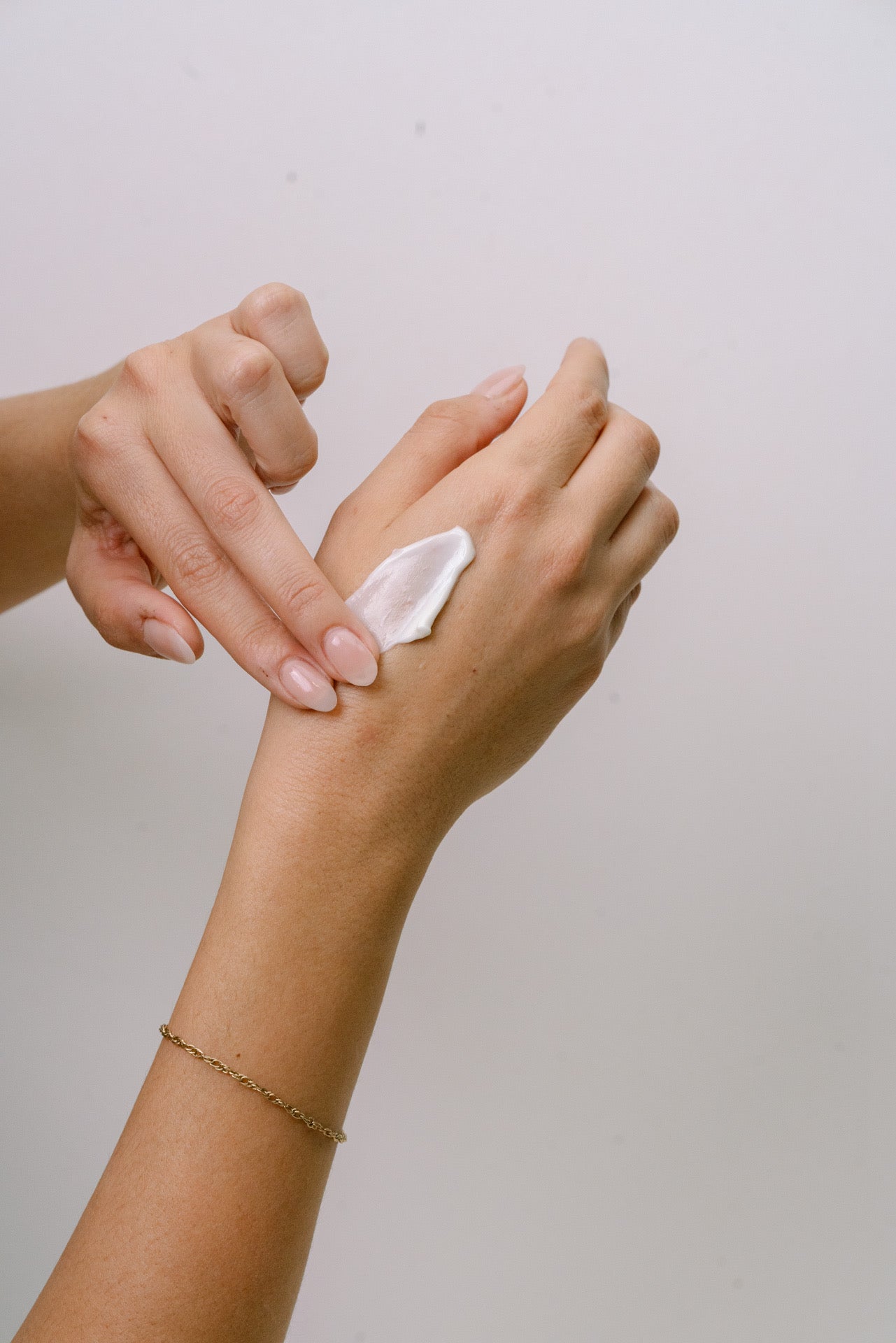 Person applying Merigold hand cream to their wrist with a neutral background