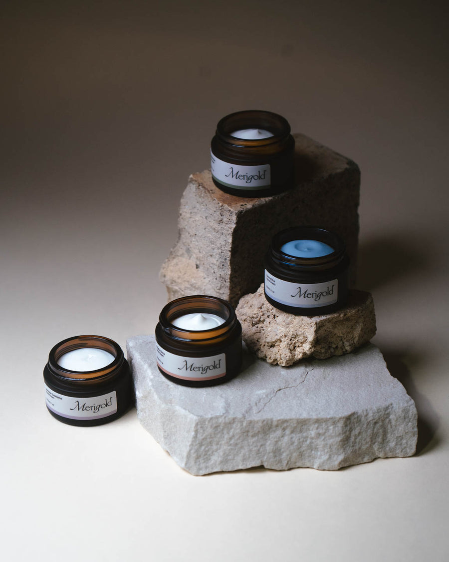 Merigold four-scent mini hand cream collection styled on stone, including Serene Blue, Mindful Citrus, Woodland Zen, and Lavender Eucalyptus. Minimal background.