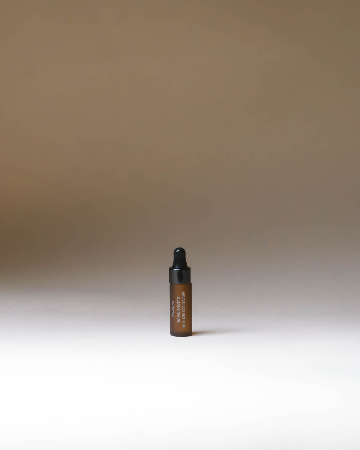 Mini travel-size Merigold Revive and Restore Cleansing Oil in amber bottle for gentle oil cleansing and makeup removal.